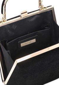 Sac à main noir avec cadre et fermoir dorés, ouvert pour montrer la doublure intérieure en tissu noir avec le nom de la marque "Kazar" sur une petite plaque en métal.