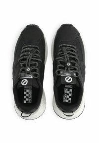 Chaussures de sport noires avec tige en tissu texturé, lacets à motif noir et blanc, et semelle blanche épaisse. Logo "No Name" visible sur la languette.