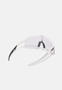 Gafas de sol deportivas con un marco blanco, lentes con tinte rosa y acentos negros. Diseño elegante, forma envolvente, material ligero.