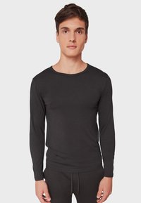Schwarzes Langarmshirt aus weichem Stoff, mit Rundhalsausschnitt und tailliertem Schnitt. Das Material wirkt glatt und leicht.