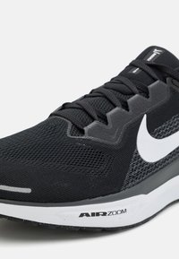 Shoe atlético preto com parte superior em malha texturizada, detalhes em cinza, swoosh branco da Nike e solado AIRZOOM acolchoado. Vista lateral.