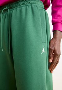 Groene trainingsbroek gemaakt van zachte katoen, met een elastische tailleband met trekkoord en een wit Jordan-logo nabij de zak.