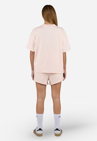 Lyserød bomulds T-skjorte med korte ermer, kombinert med matchende shorts. Har en avslappet passform, enkelt design og ensfarget tekstur.