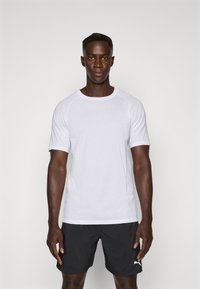 Camiseta atlética blanca de manga corta con cuello redondo y logotipo azul claro en el pecho, combinada con pantalones cortos negros. Textura suave.