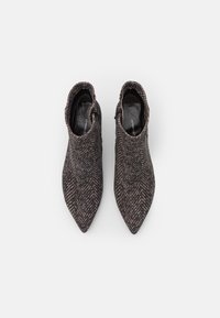 Stivaletti alla caviglia con punta affusolata caratterizzati da un motivo a spina di pesce testurizzato in marrone scuro e beige. Le zip laterali migliorano la facilità di indossarli.