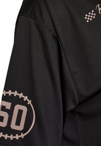 Schwarzes Sporttrikot aus strukturiertem Stoff, mit kurzen Ärmeln und einem Aufdruck mit der Nummer "50" in heller Farbe auf dem �Ärmel.