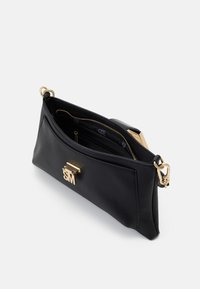 Borsa a mano in pelle nera con finitura testurizzata, hardware dorato e tasca con zip. Presenta un dettaglio del logo sul frontale.