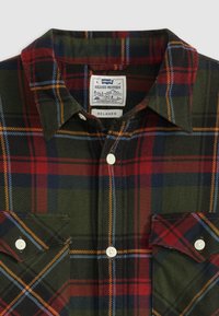 Green flannel shirt with red, blue, and orange checkered pattern, pointed collar, two buttoned chest pockets, and white buttons. Levi's label present.