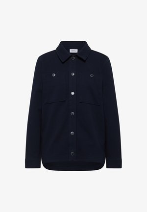 Camisa de botones azul marino con cuello, dos bolsillos en el pecho, botones a presión metálicos y un dobladillo ligeramente curvado. Textura de tela suave.