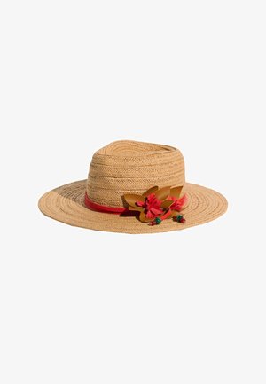 Pălărie de soare din paie împletite cu bor larg, decorată cu bandă roșie, flori din piele maro, ciucuri roșii și mărgele verzi și roșii pe fundal alb.