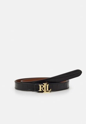 Czarny teksturowany pasek ze skóry z złotą klamrą z logo RL, zwinięty na białej powierzchni, ukazujący gładkie brązowe wykończenie wewnętrzne.