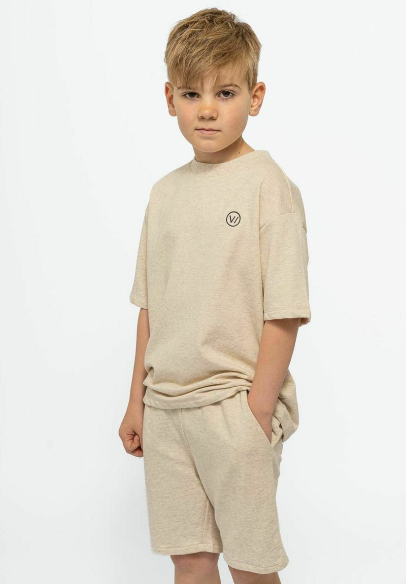 Beige puuvillane t-särk ja sobivad lühikesed püksid. T-särgil on lühikesed varrukad ja ümmargune kaelus, millel on rinnal väike logo.