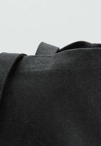Geantă neagră din pânză, cu o suprafață texturată, având un capac plat și o curea lungă și robustă atașată de fiecare parte.