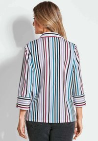 Gestreifte Bluse mit vertikalen Linien in Teal, Burgundy, Schwarz und Weiß, mit Dreiviertelärmeln und einem strukturierten Kragen.