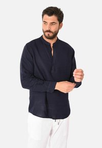 Camicia a maniche lunghe blu navy con colletto alla cinese e piastra dei bottoni, realizzata in tessuto leggero, presenta una superficie liscia e una vestibilità su misura.