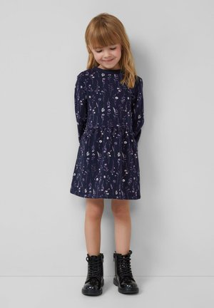 Marineblauwe bloemendress met lange mouwen,Gathered taille en een geplooide rok, gecombineerd met glanzende zwarte enkellaarsjes.