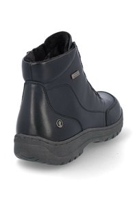 Botas de tobillo de cuero negro con suela de goma texturizada, que presentan un cierre lateral y un interior forrado suave para mayor calidez. Accento metálico cerca del talón.