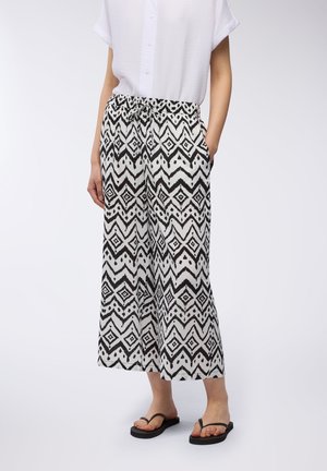 Pantaloni a righe in bianco e nero con una vestibilità ampia, caratterizzati da una stampa a rombi, una vita elastica con coulisse e tasche laterali.