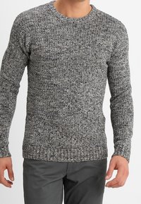 Šedý pletený svetr s texturovaným vzorem, kulatým výstřihem a žebrovanými manžetami. Nositelný s tmavě šedými kalhotami.