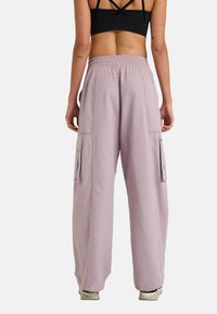 Light purple cargo pants with side pockets, elastic waistband, and loose fit. Made from soft fabric with contrast stitching details.