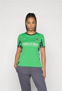 Roheline spordisärk lühikeste varrukatega, mustade aktsentidega ja külgmiste mustritega. Ees on logo ja sponsori tekst. Valmistatud kergest materjalist.