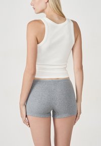 Canotta bianca a coste abbinata a boyshort grigi e testurizzati, con un design aderente, vita media e stile minimalista.