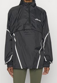 Czarna wiatrówka z półzamek, wyposażona w odblaskowe białe akcenty oraz regulowany sznurek u dołu i kaptura. Lekki materiał.