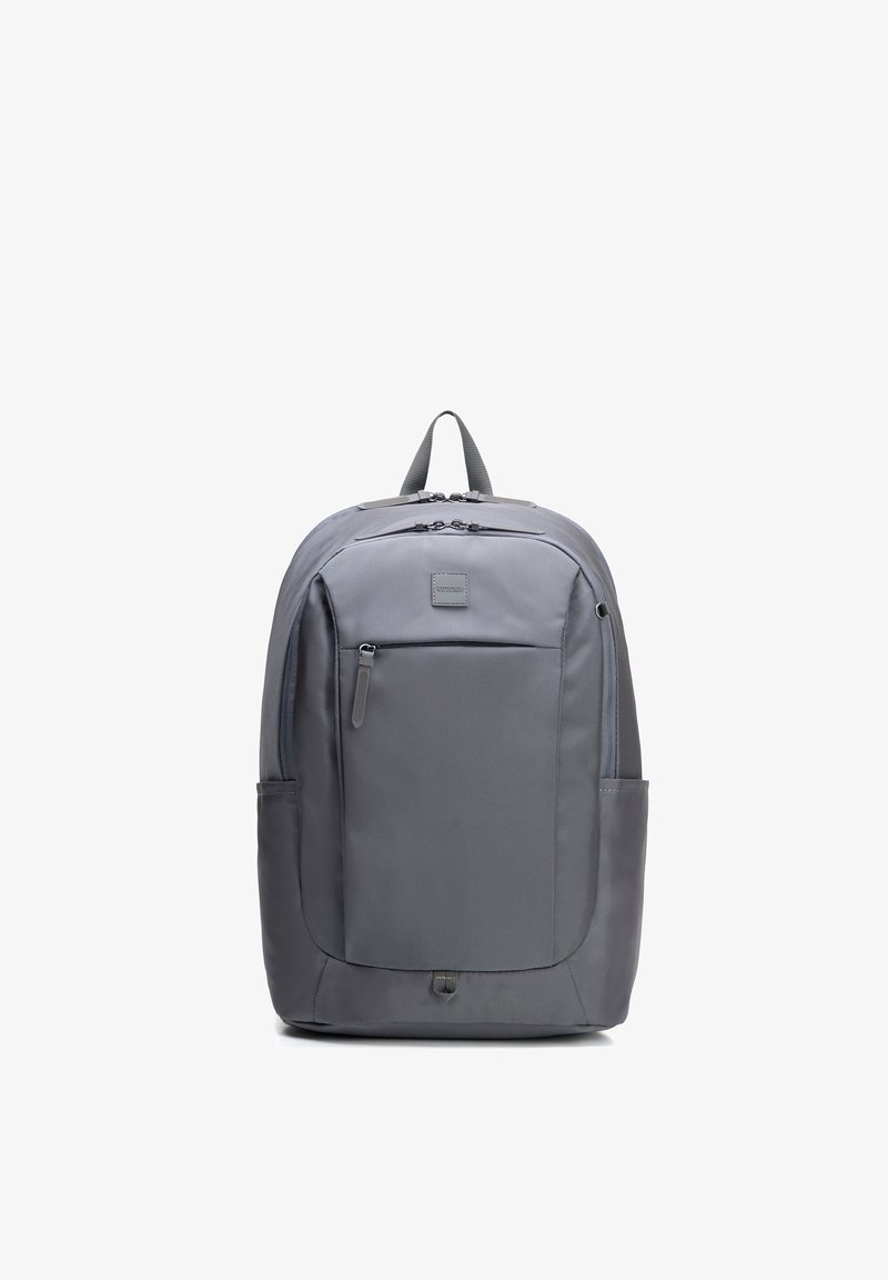 Mochila gris con bolsillo frontal con cremallera, bolsillos laterales, asa acolchada y compartimentos con doble cremallera, mostrada sobre un fondo blanco.