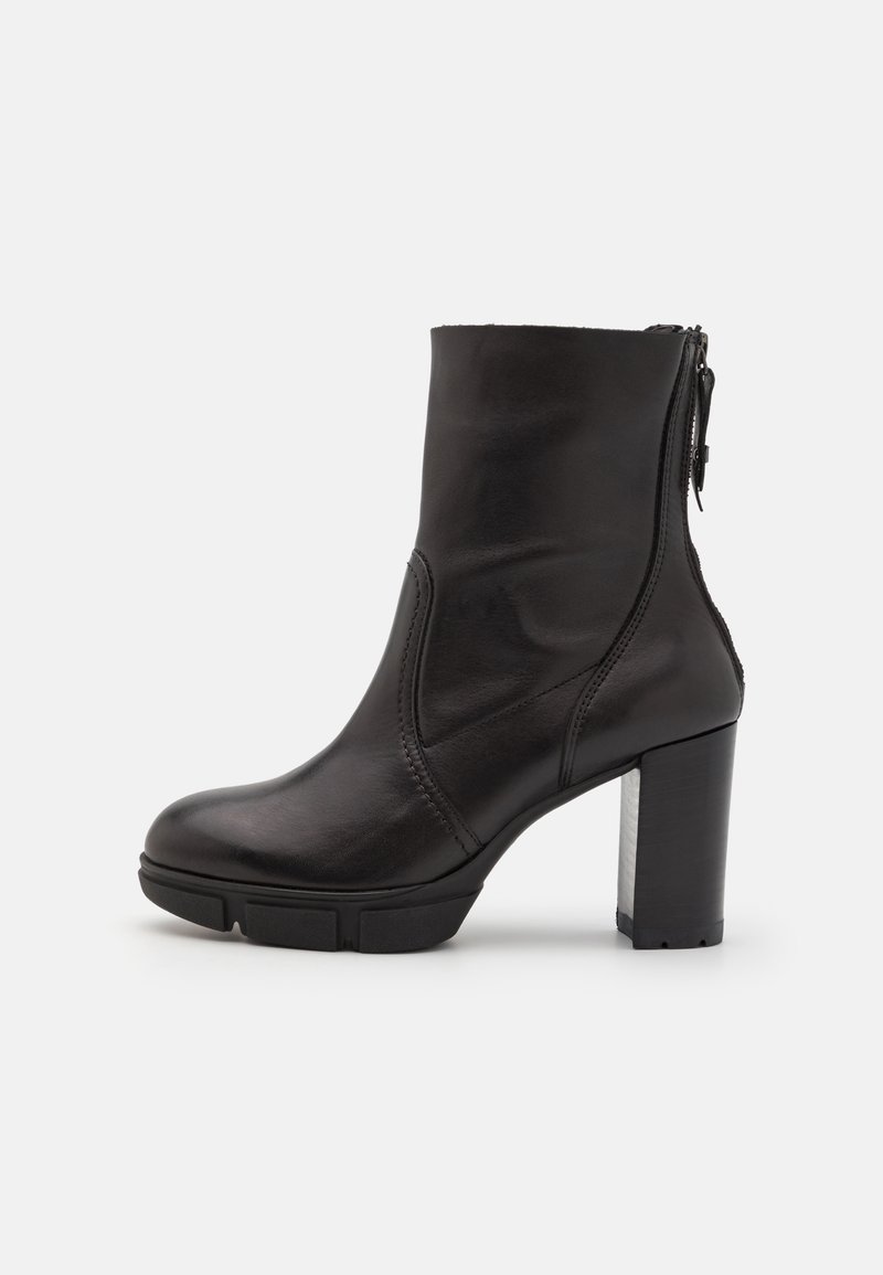 Bottine noire en cuir avec talon bloc et fermeture éclair à l’arrière, avec des détails de panneaux cousus et une semelle en caoutchouc robuste.