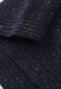 Écharpe tricotée bleu marine en laine texturée, avec un design côtelé et des éclats de blanc et de rouge, créant un motif subtil et varié.