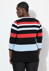 Musta pitkähihainen paita, jossa on vaakasuoria raitoja punaisena, valkoisena ja vaaleansinisenä; pyöreä pääntie ja sivurei'ät liikkuvuuden helpottamiseksi.