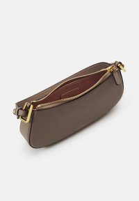 Braune Leder-Clutch mit strukturiertem Finish, goldener Reißverschluss und Beschlägen. Das Innere hat ein kontrastierendes tiefrotes Innenfutter und ein Markenetikett.