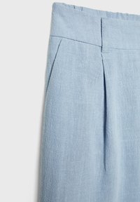 Pantalon en lin bleu clair présentant un pli avant, une ceinture et une ouverture de poche latérale sur fond blanc.