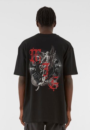 Musta puuvillapaita, jossa on yksityiskohtainen graafinen kuvasto selässä, esittäen hahmoja harmaana ja punaista väriä, jossa on monimutkaisia yksityiskohtia.