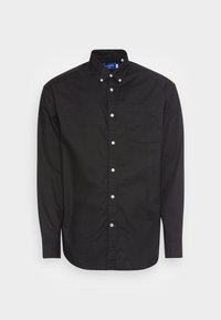 Maglietta nera a maniche lunghe in cotone, con colletto a camicia, tasca frontale e chiusura con bottoni bianchi, oltre a un orlo curvo.