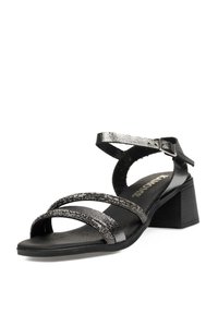 Sandalias de tacón negro con correas brillantes y texturizadas, acentos metálicos, tacón cuadrado y plantilla acolchada para mayor comodidad.