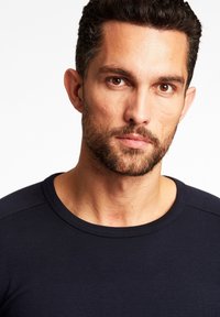 Granatowa koszula z długim rękawem i okrągłym dekoltem, uszyta z gładkiego, dopasowanego materiału. Posiada subtelną, prążkowaną teksturę na ramionach.