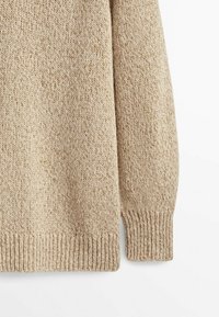 Beige knit sweater featuring a textured fabric, ribbed cuffs, and a relaxed fit. The surface has a soft, varied pattern.