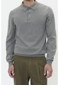 Grå stickad polo tröja med långa ärmar, tre knappar vid kragen och ribbade ärmslut. Kombinerad med olivgröna byxor.