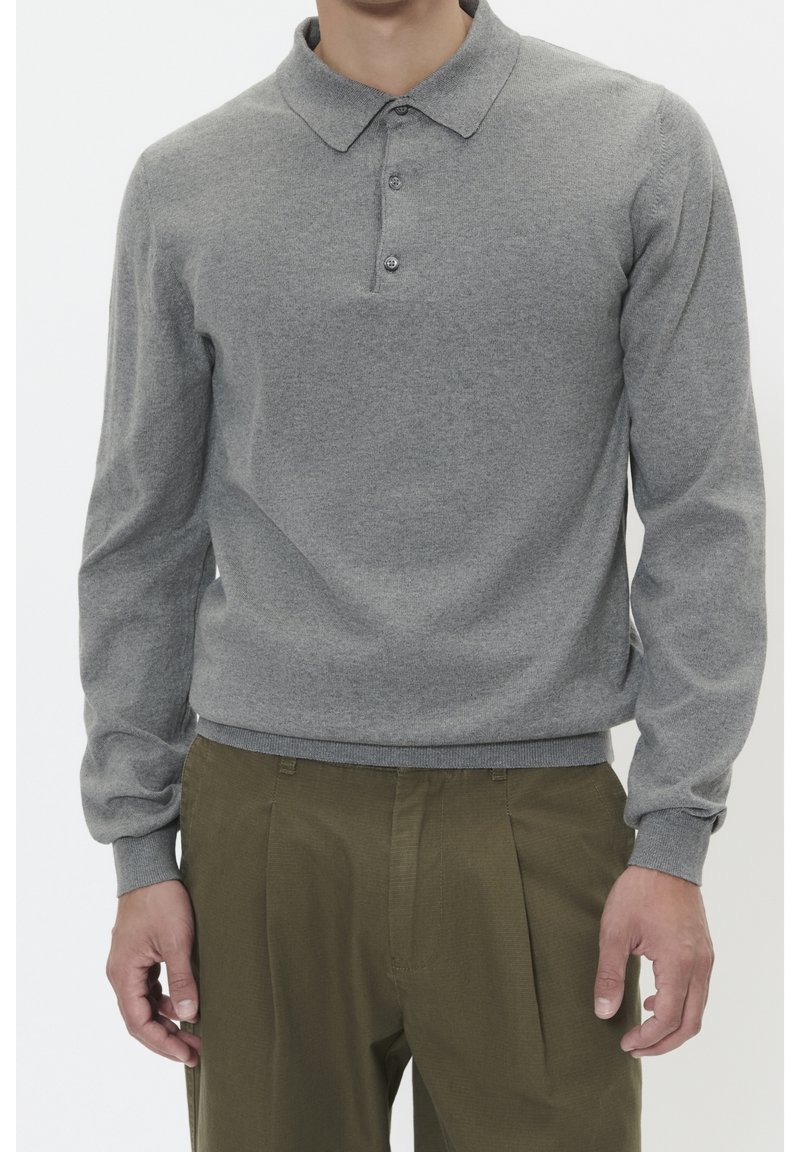 Grå stickad polo tröja med långa ärmar, tre knappar vid kragen och ribbade ärmslut. Kombinerad med olivgröna byxor.