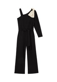 Crni kombinezon s asimetričnim dizajnom koji ima jednu dugu rukavicu i dekorativni bež volanasti naglasak na ramenu. Uključuje pojas.