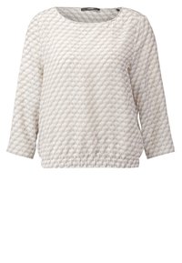 Haut à manches longues en beige clair, avec un motif hexagonal texturé, un col rond et une base froncée pour un ajustement décontracté.