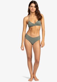 Olivgrön bikiniset med triangulärt topp och höga byxor. Slät textur, minimalistisk design och justerbara remmar.