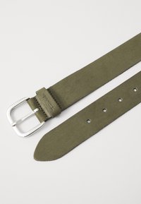 Ceinture en daim vert olive avec une boucle en métal argenté, dotée d'un renforcement en cuir au niveau de la boucle et de plusieurs trous pour un ajustement de taille.