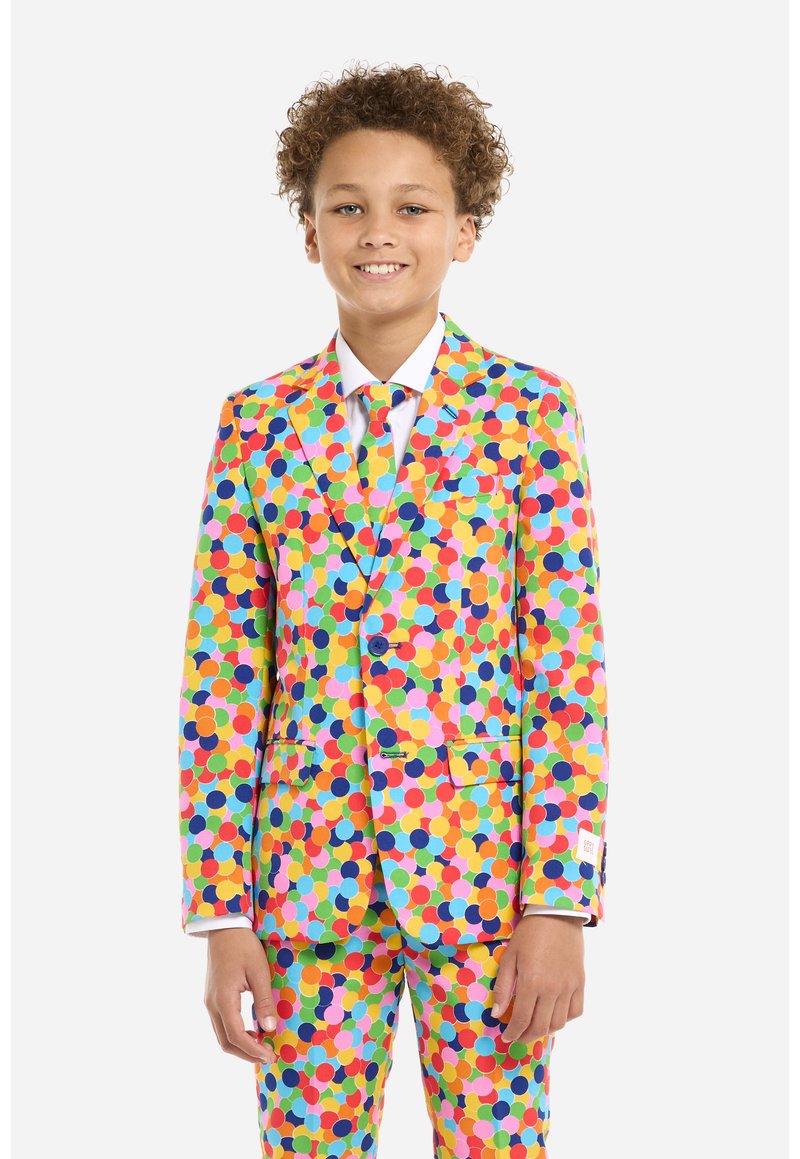 Un completo colorato composto da un blazer e pantaloni, con un motivo di grandi pois multicolori su uno sfondo giallo brillante.