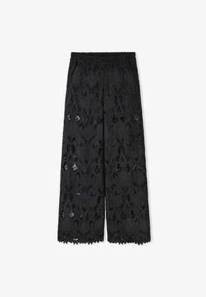 Black wide-leg pants made from lace with floral patterns. Features an elastic waistband and scalloped hem. Semi-sheer texture.