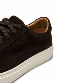 Dunkelbraune Wildlederschuhe mit passenden Schnürsenkeln und einer weißen Gummisohle. Verfügt über dezentes Branding und ein glattes Innenfutter.