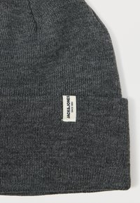 Γκρι πλεχτό σκουφάκι με αναδιπλούμενο στρίφωμα και λευκή ετικέτα που αναγράφει "JACK & JONES". Το ύφασμα φαίνεται μαλακό και υφασματώδες.