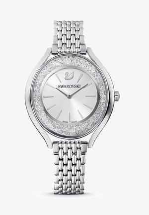 Sølvur med rund urskive, prydet med glitrende krystaller omkring urkassen, og en struktureret metalnetrem. Brandlogo synligt.