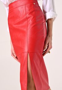 Roter Leder-Bleistiftrock mit hohem Schlitz und glatter Textur. Besitzt eine figurbetonte Silhouette und einen kleinen silbernen Akzent am Bund.